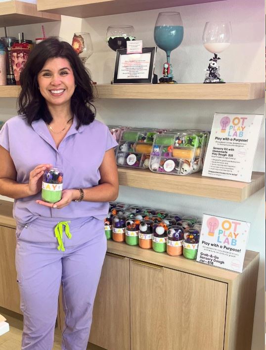 Person in purple scrubs holding a product in a store setting with shelves and signs.