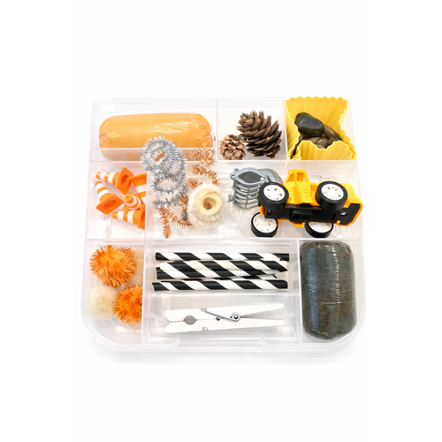 Clear plastic container with various decorative items including pom-poms, ribbons, and a toy car on a white background.